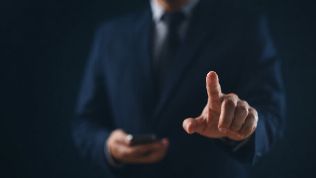 Businessman pointing hand on invisible virtual screen with dark