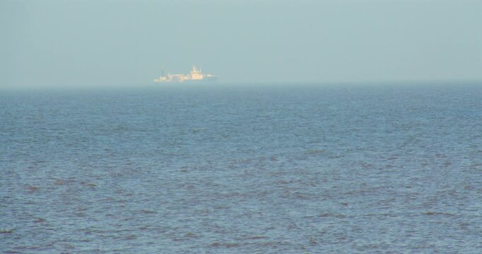 Wide shot of the North Sea wave large ship in distant background