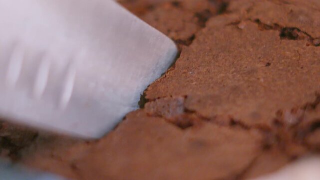 Close-up of Knife Cutting Up Freshly Baked Homemade Chocolate Brownie.