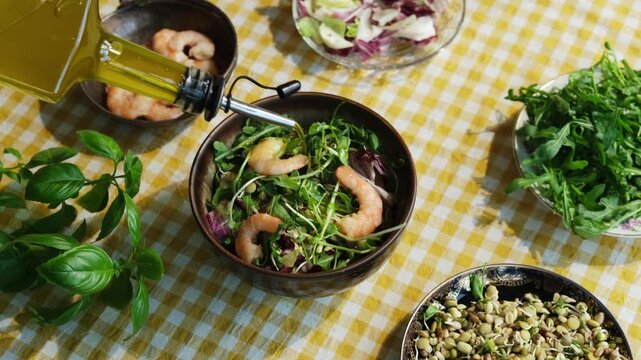 Heathy dinner or breakfast. Salad with shrimps, basil, arugula, lettuce and bean sprouts. Preparing summer salad pouring olive oil.