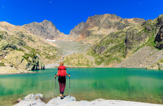 female hiker with red backpack looking at turquoise lac blanc in chamonix french alps