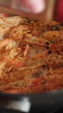 Vertical video. Sprinkling paprika to pan with frying tiger prawns. Shrimps cooking. Food prep.