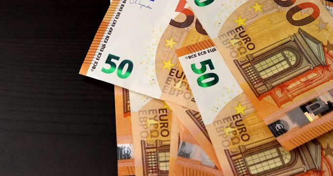 Stack of 50 euro paper bills dropping onto a desk representing wealth, investment payout, and prosperity, showing financial transactions, economic growth, and banking concept.