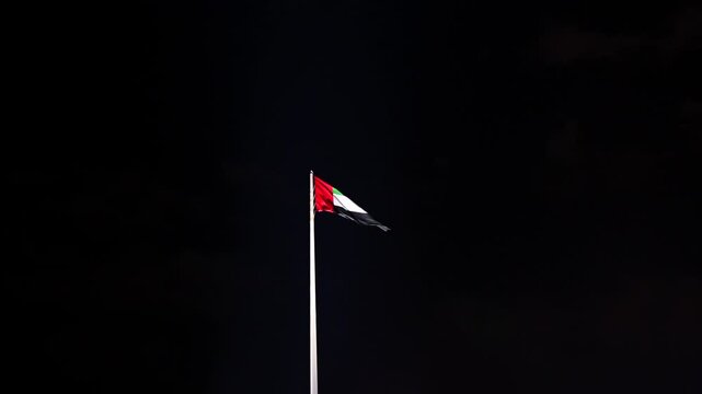 The UAE flag flying gracefully at night.