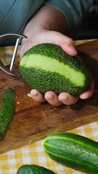 Vertical video. Food prep. Woman peeling avocado for making summer diet salad