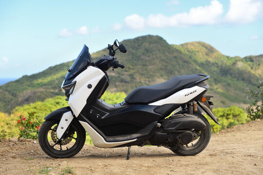 Yamaha NMAX scooter with green hills of Bali Indonesia in background.