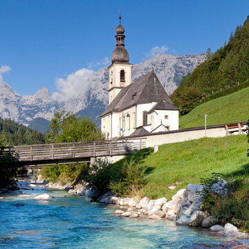 Charming Alpine Village with Church by a Mountain River in Summer
