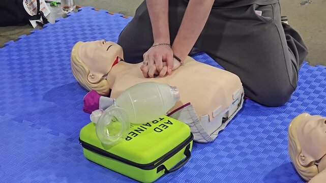 CPR Training and First Aid Instruction with Mannequin, AED Trainer, and Resuscitator Mask on Foam Mat