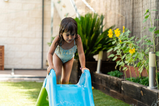Young white girl climbing a blue water slide