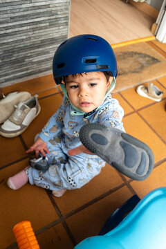 Toddler wearing helmet holding shoe sitting featuring a white model