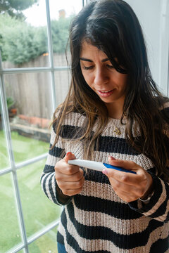 Young white woman holding a test device and looking