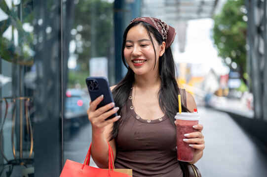 Young Asian Woman Looking at Smartphone Screen while Shopping