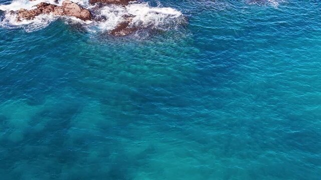 Aerial View of Turquoise Ocean Waves Crashing Against Coastal Rocks
