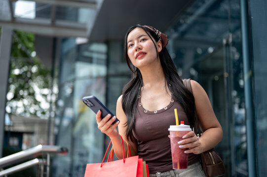 Young Asian Woman Looking Up while Shopping with Phone