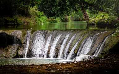 Water falling over natural rock cascade in forest stream © Pawich Sattalerd