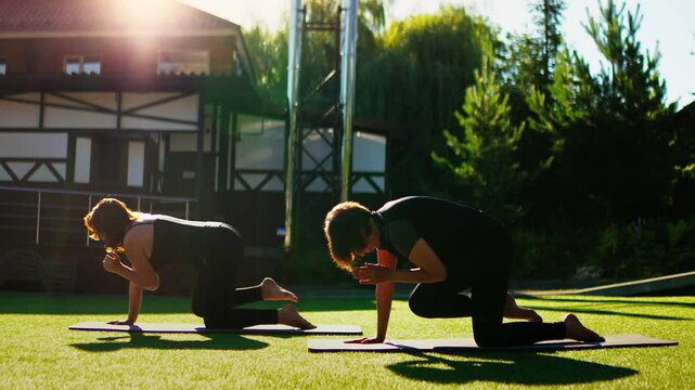 Elderly women practicing slow motion Pilates balance exercises outdoors on yoga mats, extending arms and legs for strength, flexibility, and mindful stability