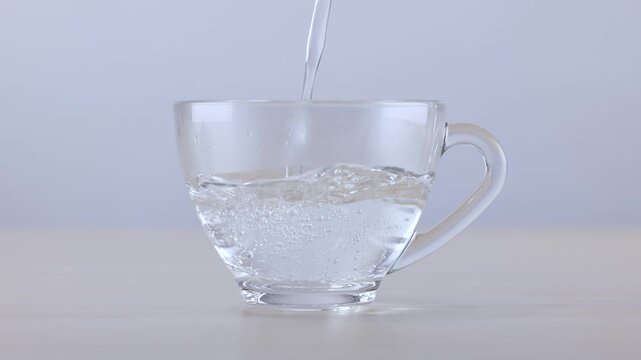 Fresh Water Pouring into a Clear Glass Cup on Wooden Table