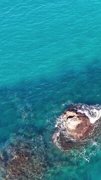 Aerial View of Turquoise Ocean Waves Crashing Against Coastal Rocks