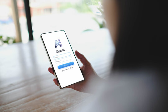 Person holding smartphone vertically displaying generic sign in user interface template in bright indoor setting.