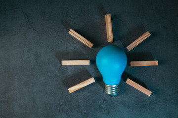 Idea concept with blue light bulb and wooden blocks on black background © Artvibe