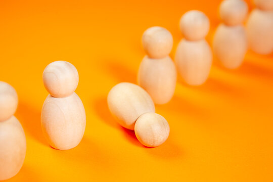 Wooden figures of people stand in a row on an orange background