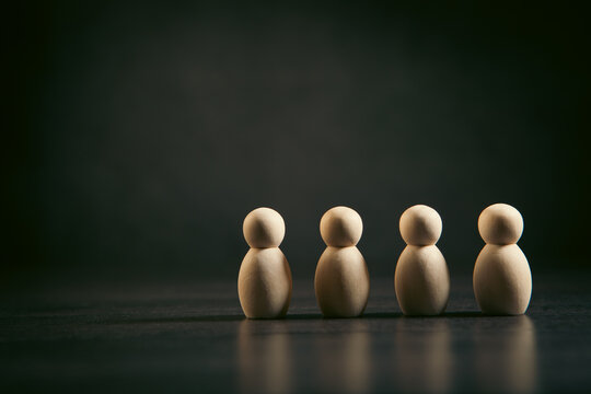 Wooden figures of people stand in a row on a black background