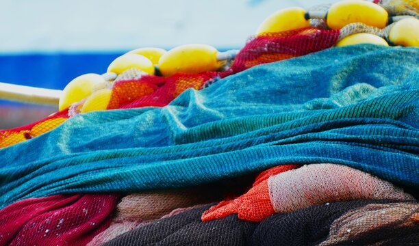 Fishing nets on the boat by the blue sea in Mediterranean city, nautical equipment background