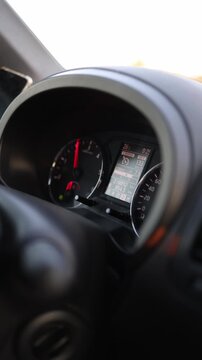 Vertical screen Close up view of car dashboard shows illuminated tachometer and digital instrument display while vehicle travels at highway speeds during an evening drive

