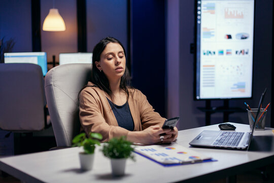 Caucasian business owner talks with colleagues by mobile phone as part of normal office activity in a modern office environment after an extended business day.