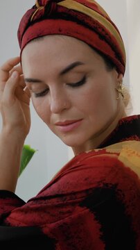 Luxury satin head wrap with tropical sunset print styled with elegant low bun and statement earrings.