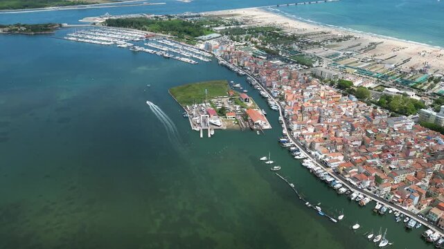Aerial drone footage of Chioggia, Italy: historic canals, colorful waterfront, fishing boats and charming Venetian lagoon scenery under clear daylight. Ideal for travel and tourism projects.