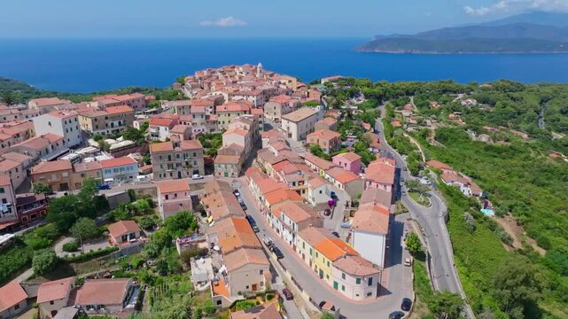 Aerial view of the historic hilltop town of Capoliveri on Elba Island, Tuscany, Italy, featuring terracotta rooftops, Mediterranean vegetation and stunning sea views.