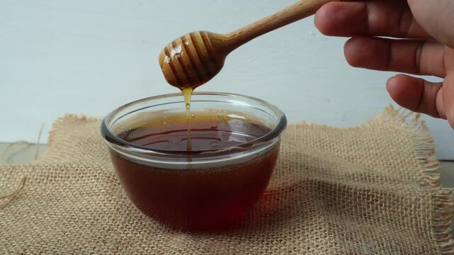 Hand dripping honey from honey dipper