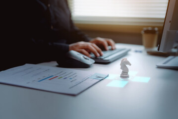 Business strategy concept with knight chess piece on glowing digital interface on office desk with businessman working in background © harit
