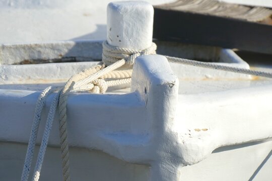 White wooden fishing boat with ropes in a harbor in Mediterranean city , nautical equipment background