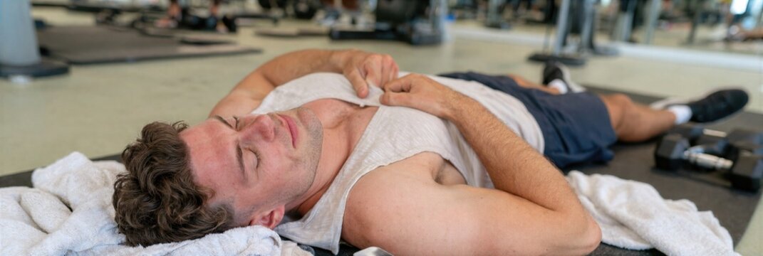 Exhausted man lying on gym floor after workout