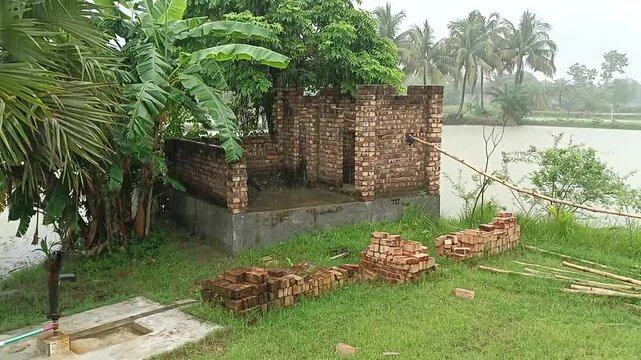 Abandoned brick house ruin in tropical landscape, crumbling red brick structure by a river, derelict rural building surrounded by palm trees