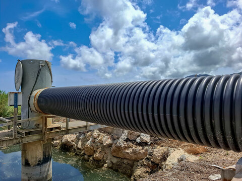 Close up of modern corrugated polyethylene pipe attached to concrete water control tower over canal in Pego Oliva Marsh