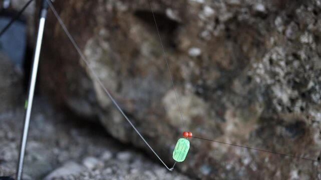 Close view of fishing rig with line sinker and small beads prepared beside a rod showing detailed tackle setup before casting bait into the sea during recreational angling

