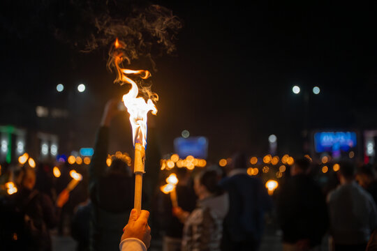 Hand holding a burning torch during nighttime procession