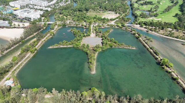 Drone footage flying forward from an oblique 45-degree top-down perspective toward a starfish-shaped artificial peninsula surrounded by a man-made lake in Nha Trang, Vietnam. 