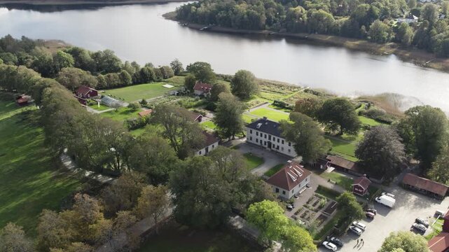 Aerial view of Rada sateri manor and grounds by a lake, surrounded by trees and gardens