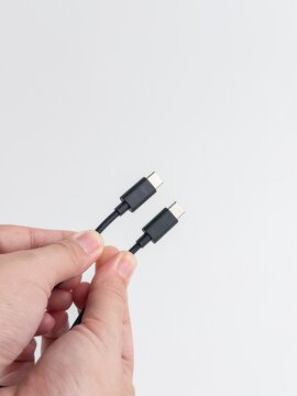 Person hand holding black USB type C charging and data cable isolated on white background