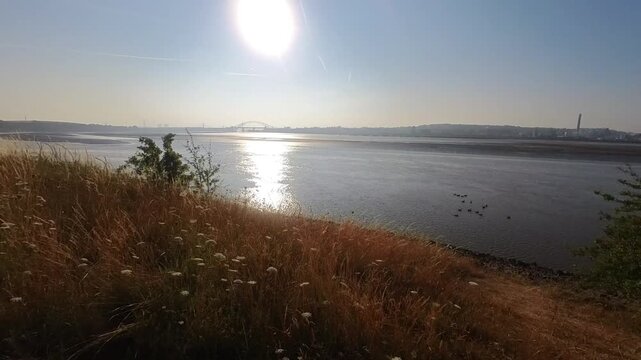 Shimmering sunlit Mersey river golden banks seen from Pickering's pasture nature reserve