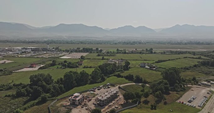 Tirane Albania Aerial v4 low flyover above rural Nd&euml;rmjet&euml;s and Rinas, revealing patchwork farmland, residential settlements and distant mountains - Shot with Mavic 3 Pro Cine - July 10th 2024