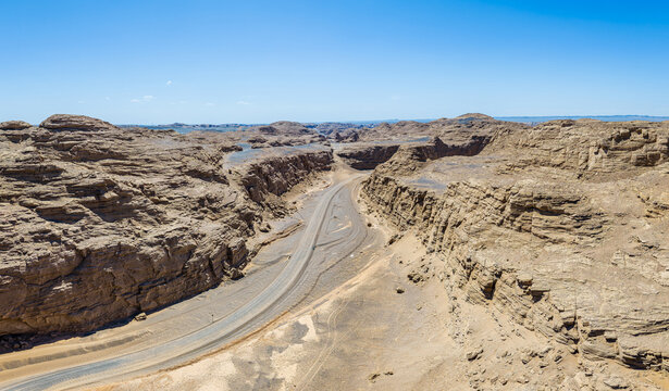 Winding dirt road through a deep canyon in the desolate yardang desert of Dahaidao, Xinjiang, China