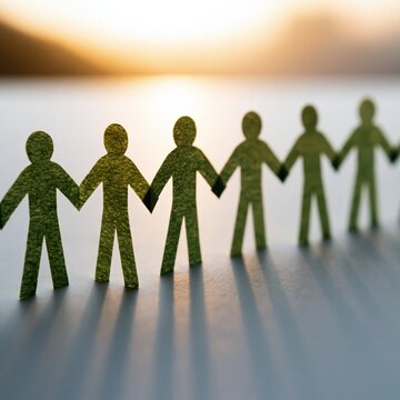 Green paper people chain holding hands silhouette at sunset for community background and teamwork banner promoting unity and environmental support