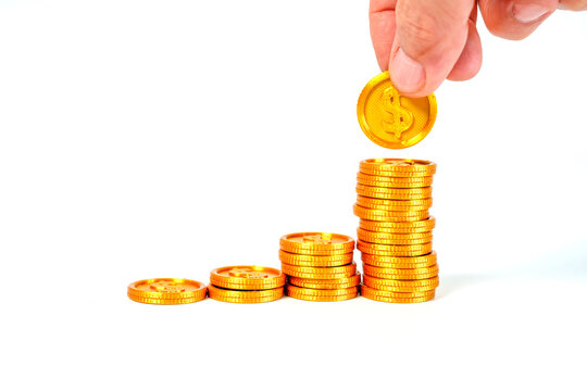 Person hand putting gold dollar coin on rising stack of coins. Concept of financial growth, savings, and investment success. Professional business and economy photography on white background.