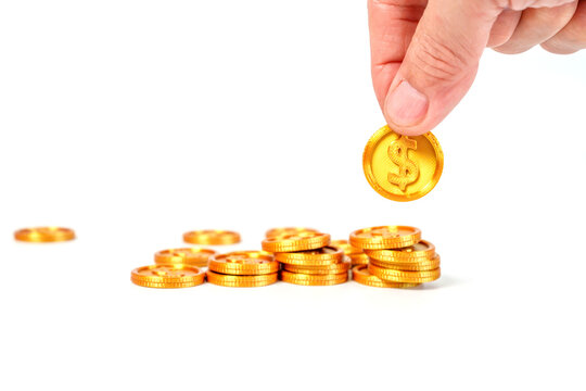 Human hand placing a gold dollar coin onto stacks of coins on a white background. Financial growth, saving, investment, and wealth concept. Professional composition for business and finance themes.