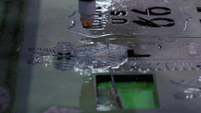 Innovative sparkling laser cutter carves out snowflake pattern on metal sheet with water closeup. Robotized lathe device cuts out intricate details at factory